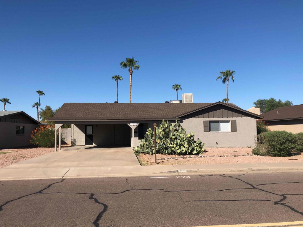 A house with a brown roof and a driveway in front of it.