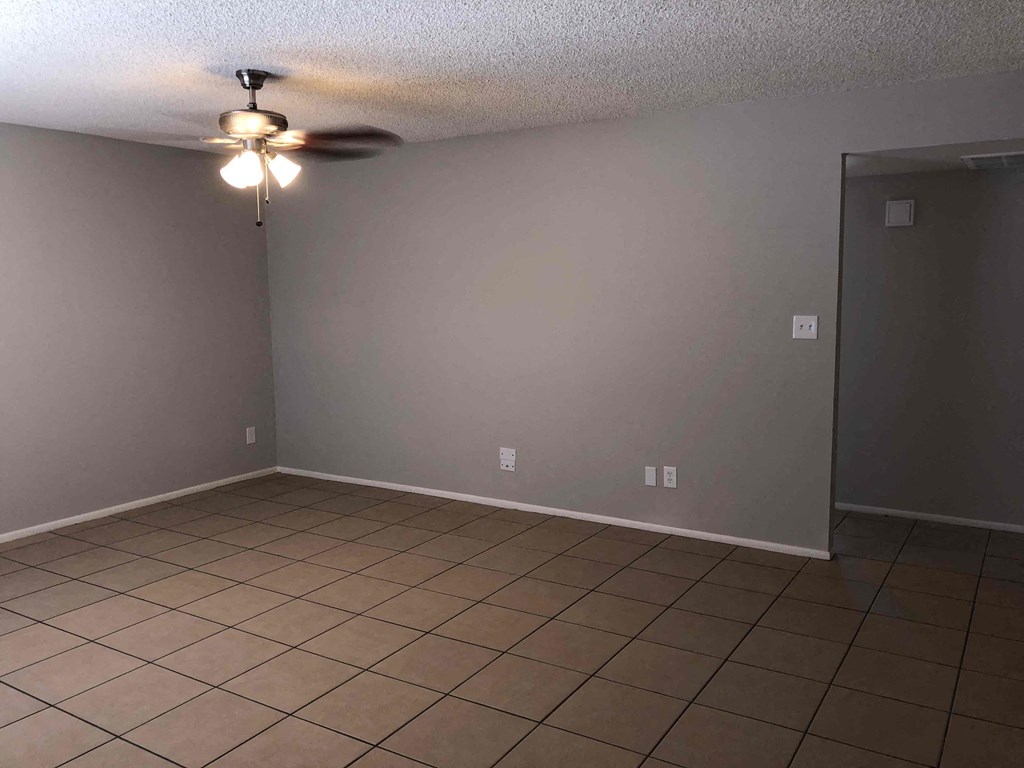 A room with a ceiling fan and tile flooring.