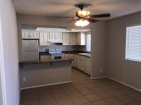 A kitchen with white cabinets and a ceiling fan.