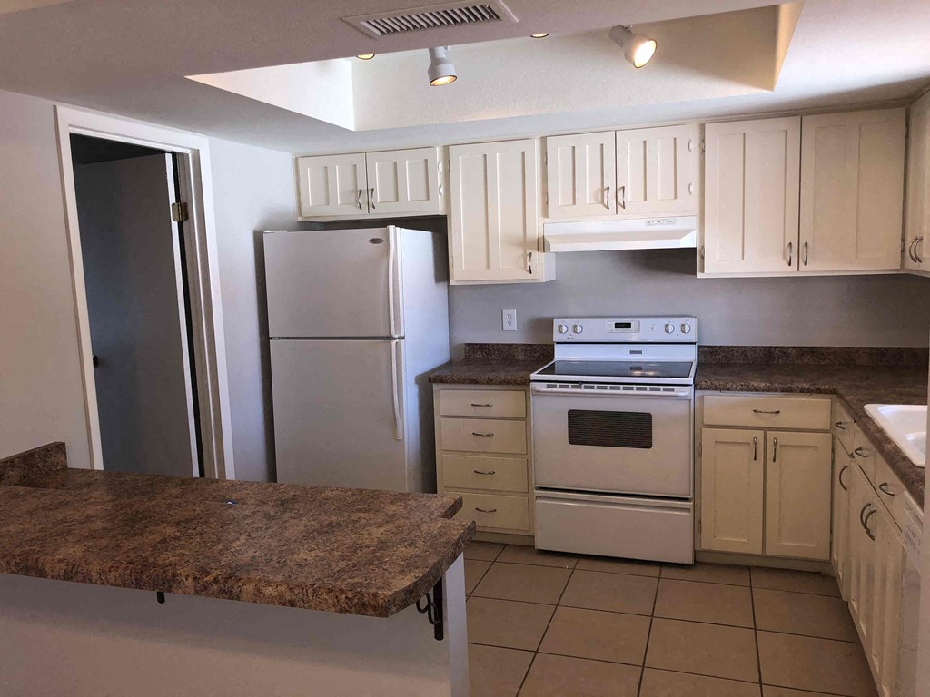 A kitchen with a granite counter top and white appliances.