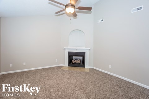 the living room has a fireplace and a ceiling fan