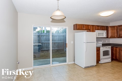 a kitchen with a refrigerator and a backdoor to a backyard