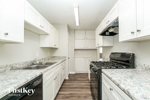 a kitchen with white cabinets and granite counter tops and a black stove