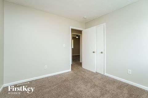 a bedroom with white walls and carpet and a door to a hallway