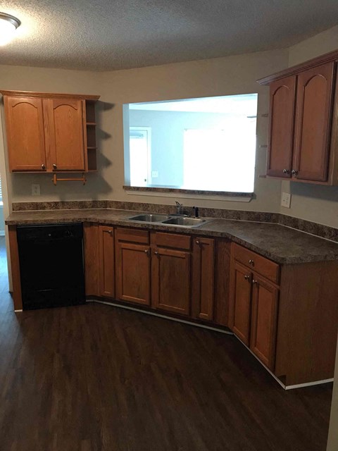 A kitchen with wooden cabinets and a black dishwasher.