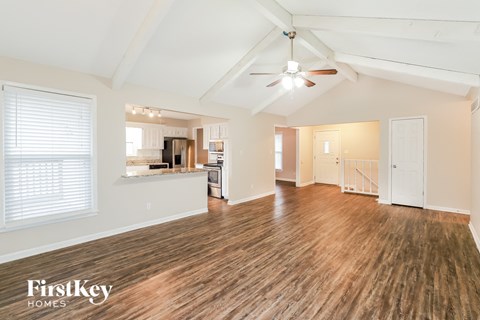 A spacious room with wooden floors and a ceiling fan.