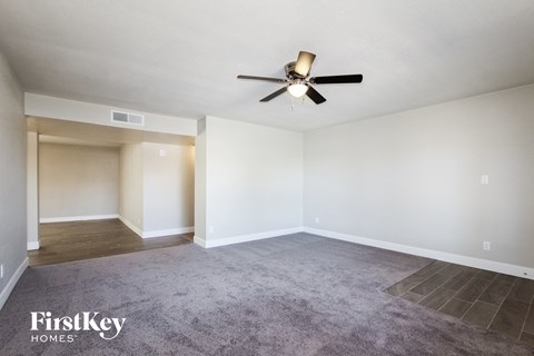 A spacious room with a ceiling fan and a carpeted floor.