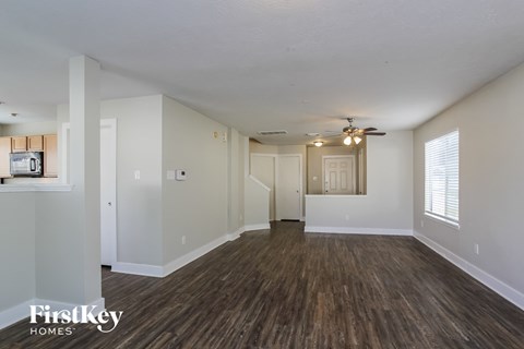 A spacious room with wooden flooring and a ceiling fan.