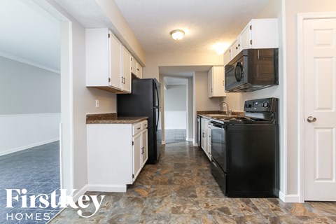 A kitchen with black appliances and white cabinets.