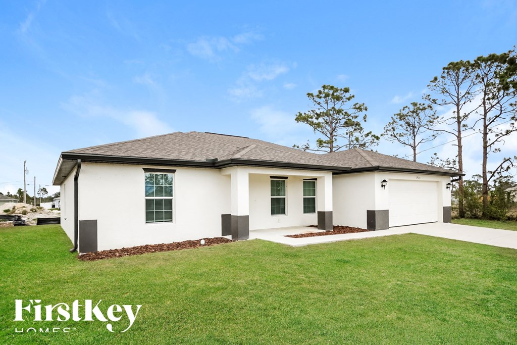 A white house with a black roof and a garage door.
