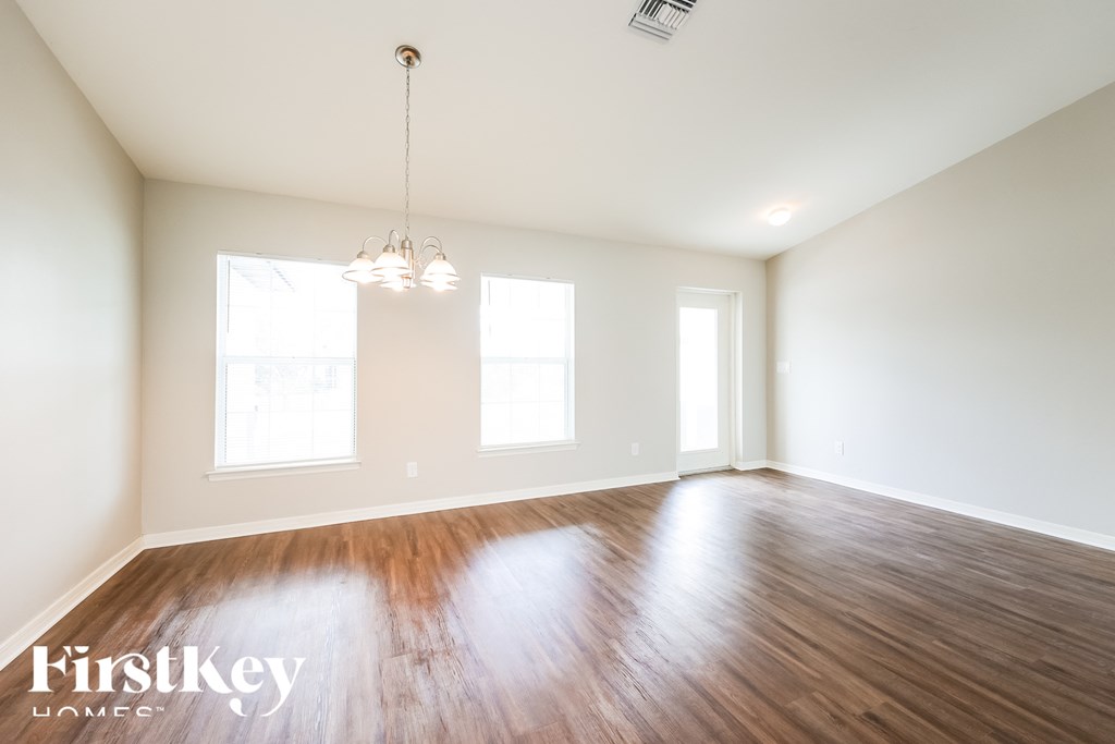 A room with wooden floors and a chandelier hanging from the ceiling.