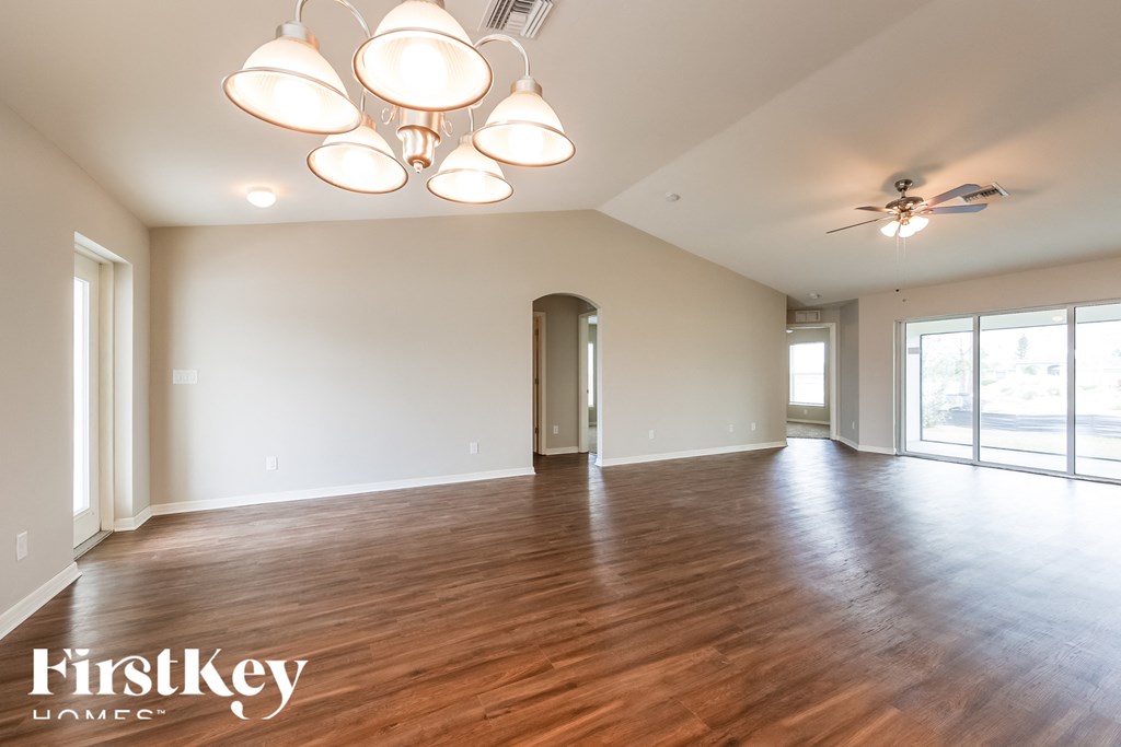 A spacious room with wooden floors and a ceiling fan.