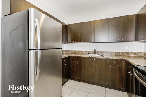 A modern kitchen with a stainless steel refrigerator and wooden cabinets.