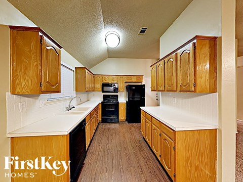 a kitchen with wooden cabinets and white counter tops and a black refrigerator