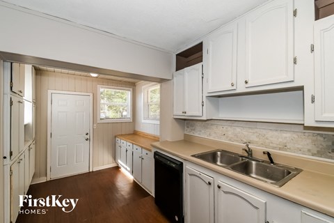 A kitchen with white cabinets and a wooden floor.