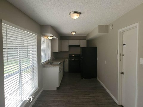 a kitchen with a large window and a black refrigerator