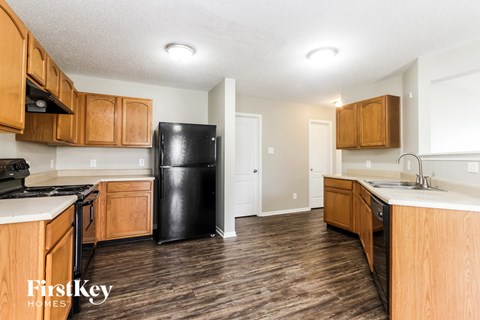 A kitchen with wooden cabinets and a black fridge.