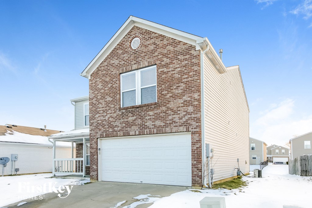 a brick house with a white garage door in the snow