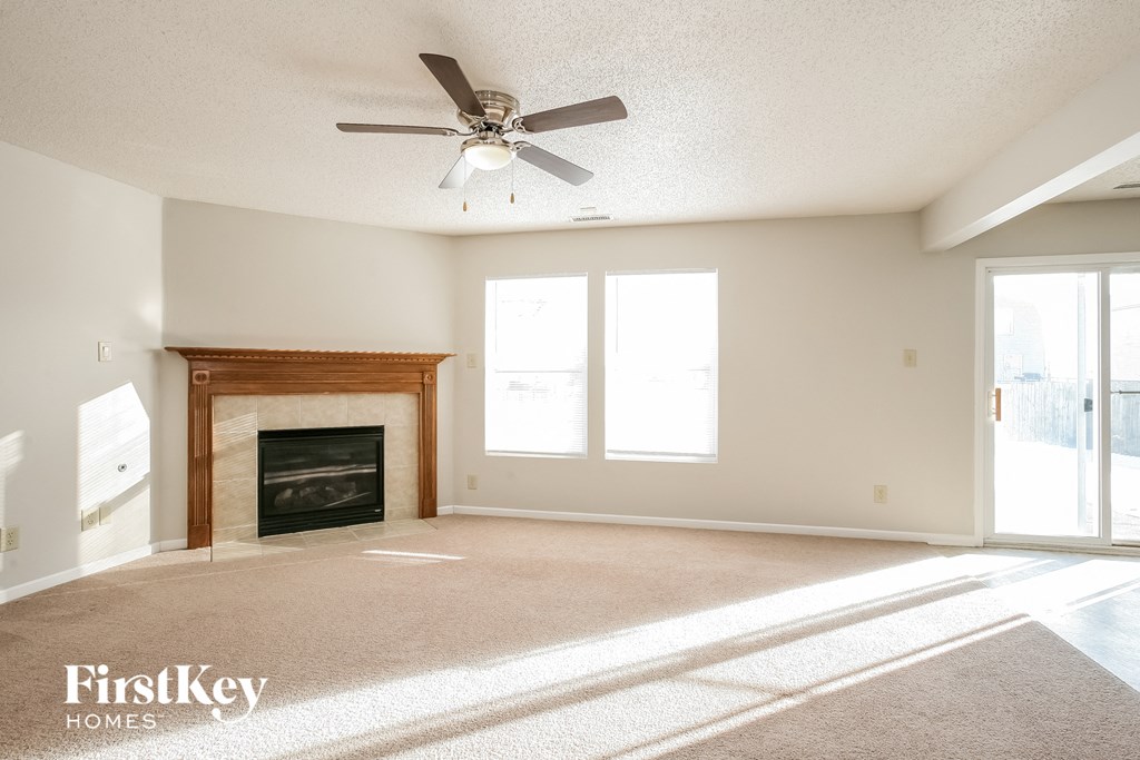 an empty living room with a fireplace and a ceiling fan