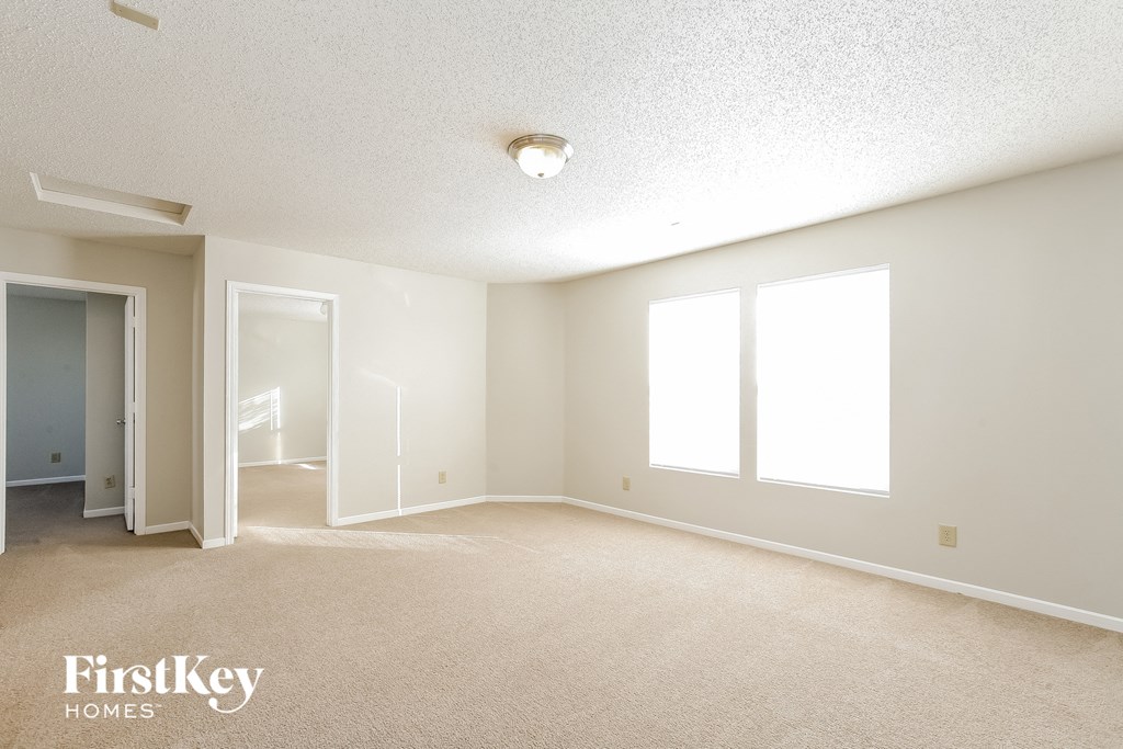 a spacious living room with carpet and a door to a hallway