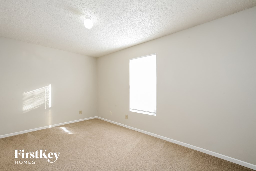 a bedroom with white walls and carpet and a window