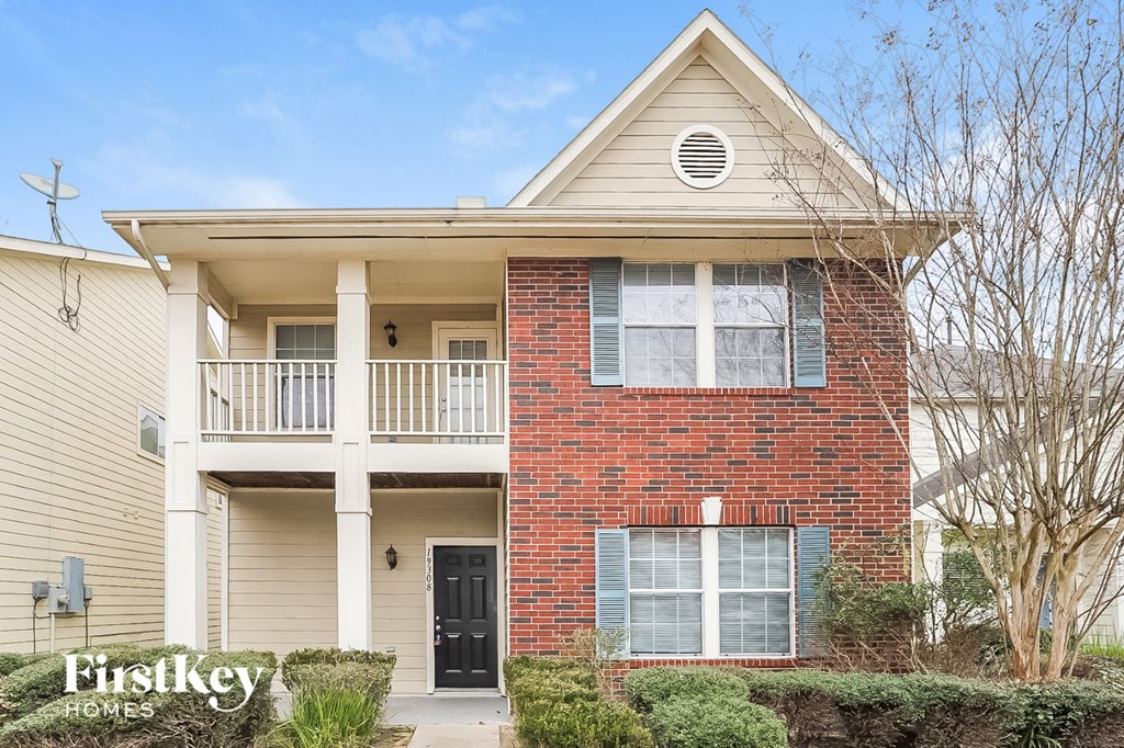 a brick house with a balcony and a black door