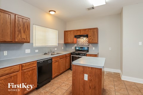 a kitchen with wooden cabinets and a black dishwasher and a sink
