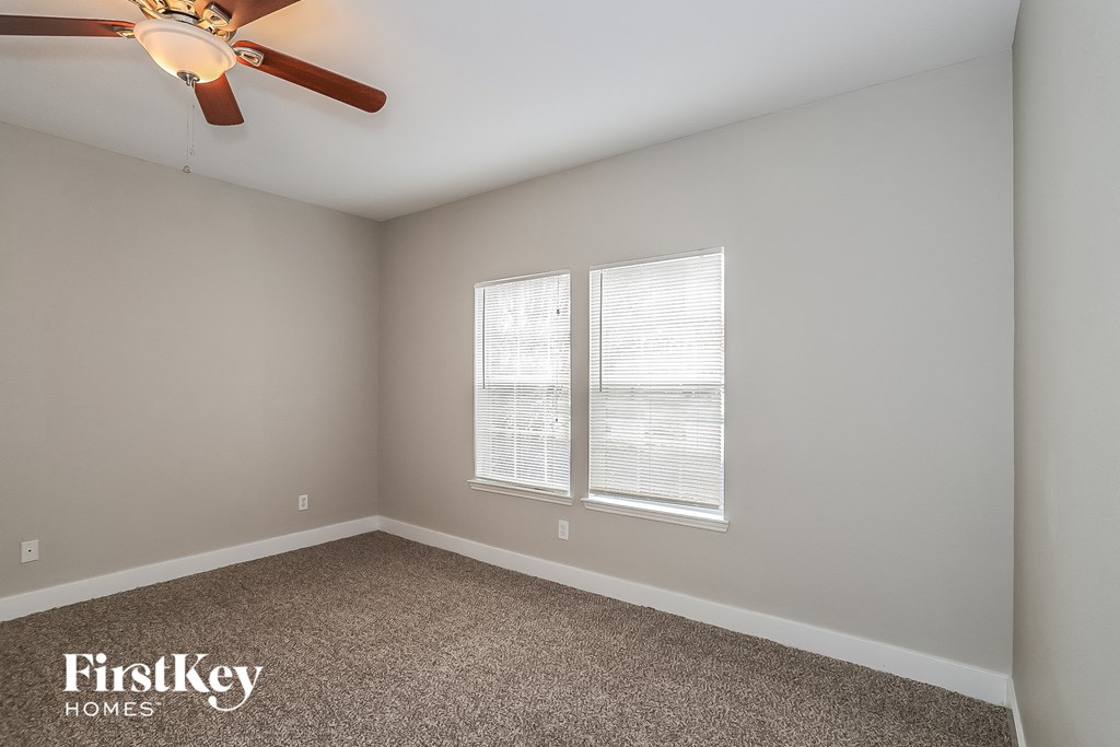 a bedroom with a ceiling fan and two windows