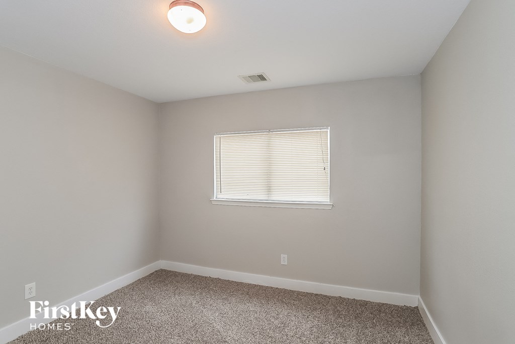 a bedroom with white walls and carpet and a window