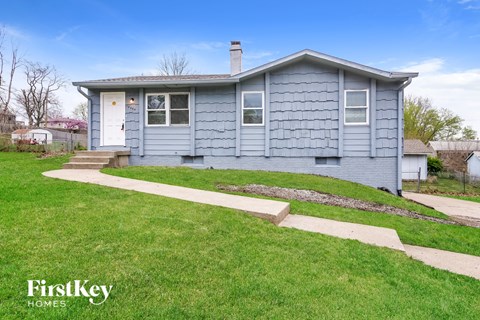 A blue house with a white door and windows is for sale.