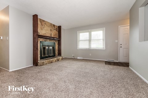 A spacious room with a fireplace and carpeted floor.