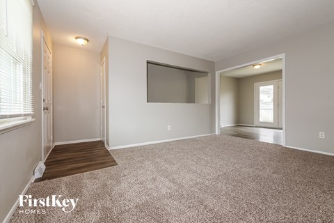 A spacious living room with a flat screen TV mounted on the wall.
