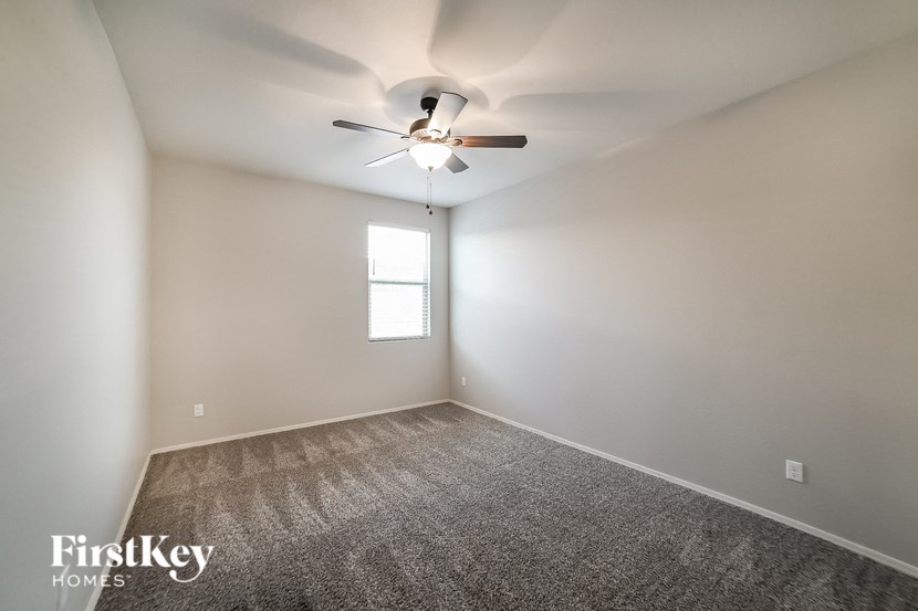an empty room with a ceiling fan and a window