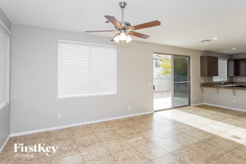 an empty living room with a ceiling fan and a kitchen