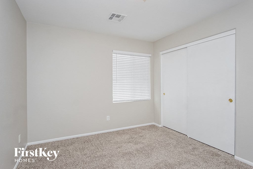 a bedroom with white walls and carpet and a closet