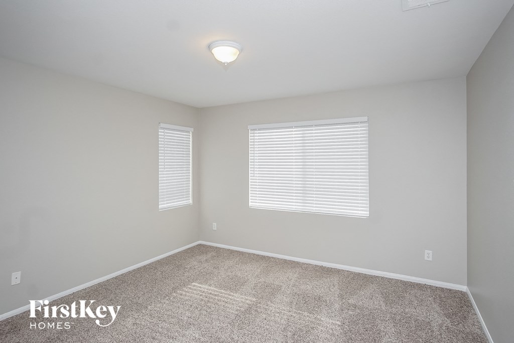 the spacious bedroom with carpeted flooring and two windows