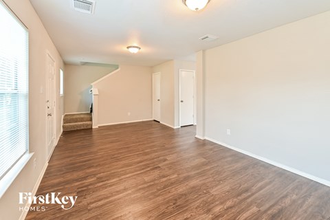 A spacious room with wooden flooring and white walls.