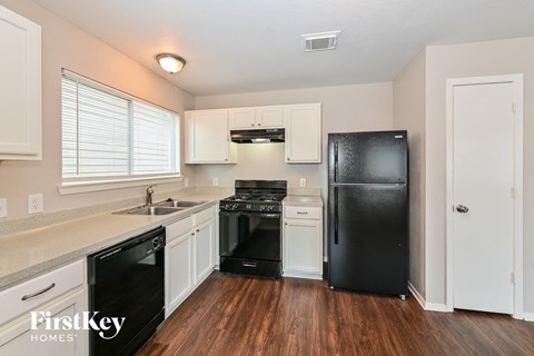 A kitchen with a black fridge and white cabinets.