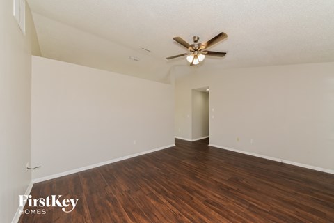 a living room with hardwood flooring and a ceiling fan