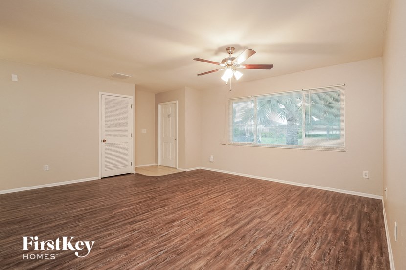 an empty living room with a ceiling fan and a window