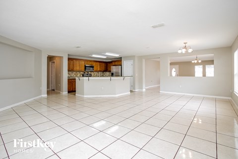 A spacious living room with a kitchen in the background.