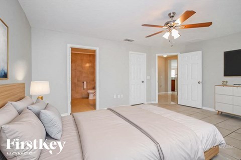 A bedroom with a large bed and a ceiling fan.