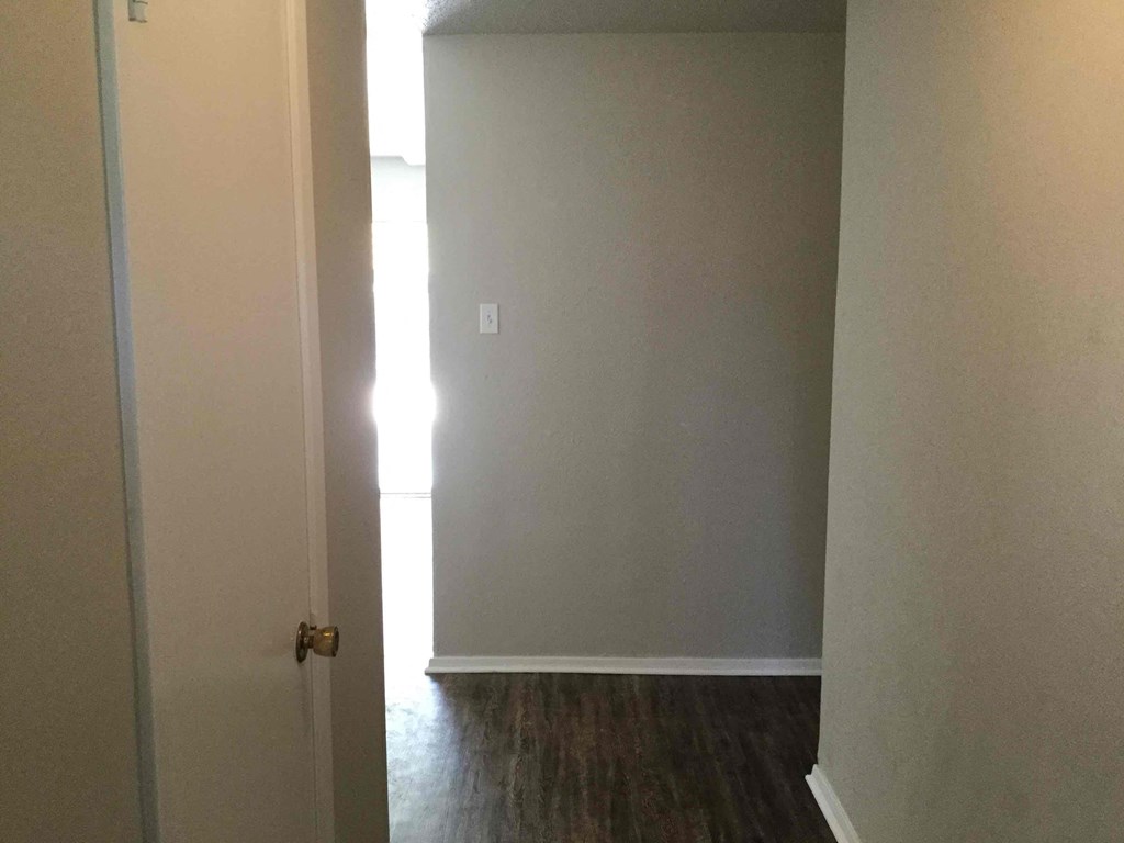 an empty room with a door open and a hallway to a closet