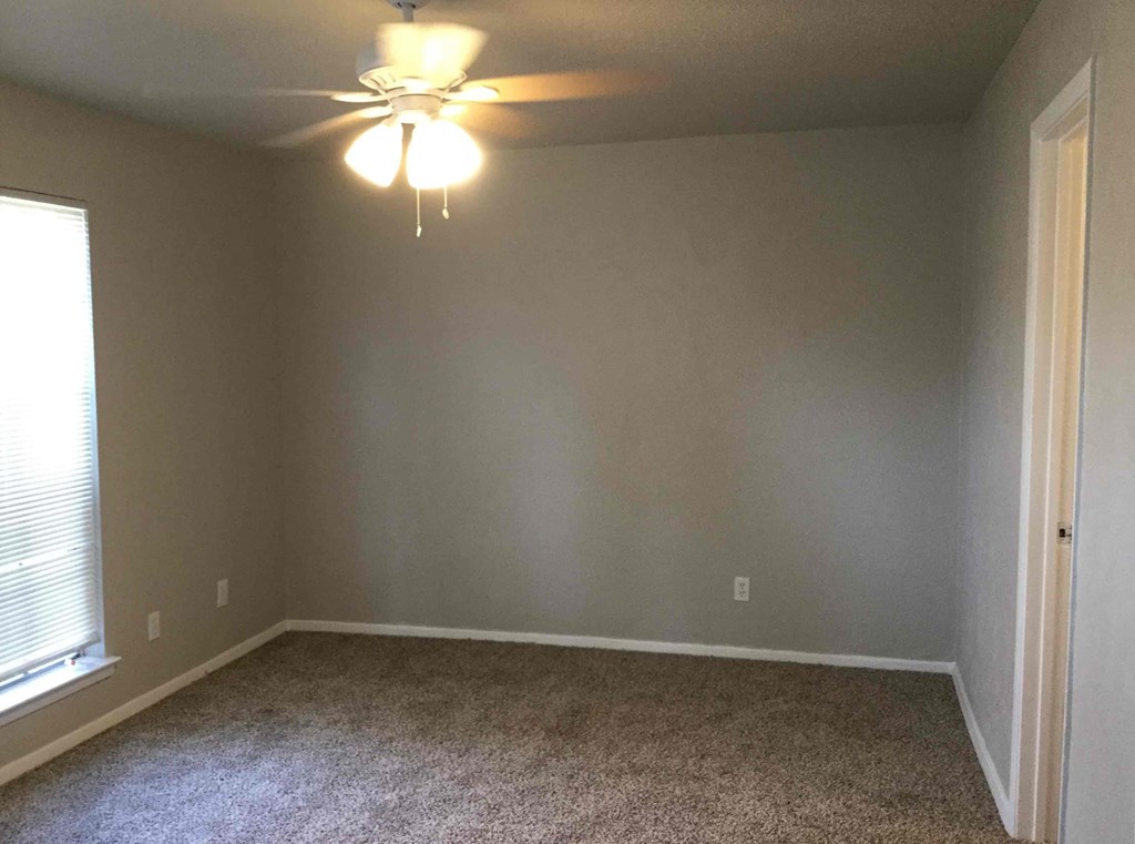 a empty room with a ceiling fan and a window