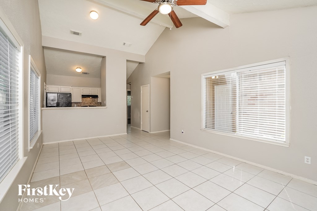 A spacious room with a ceiling fan and a kitchen area in the background.