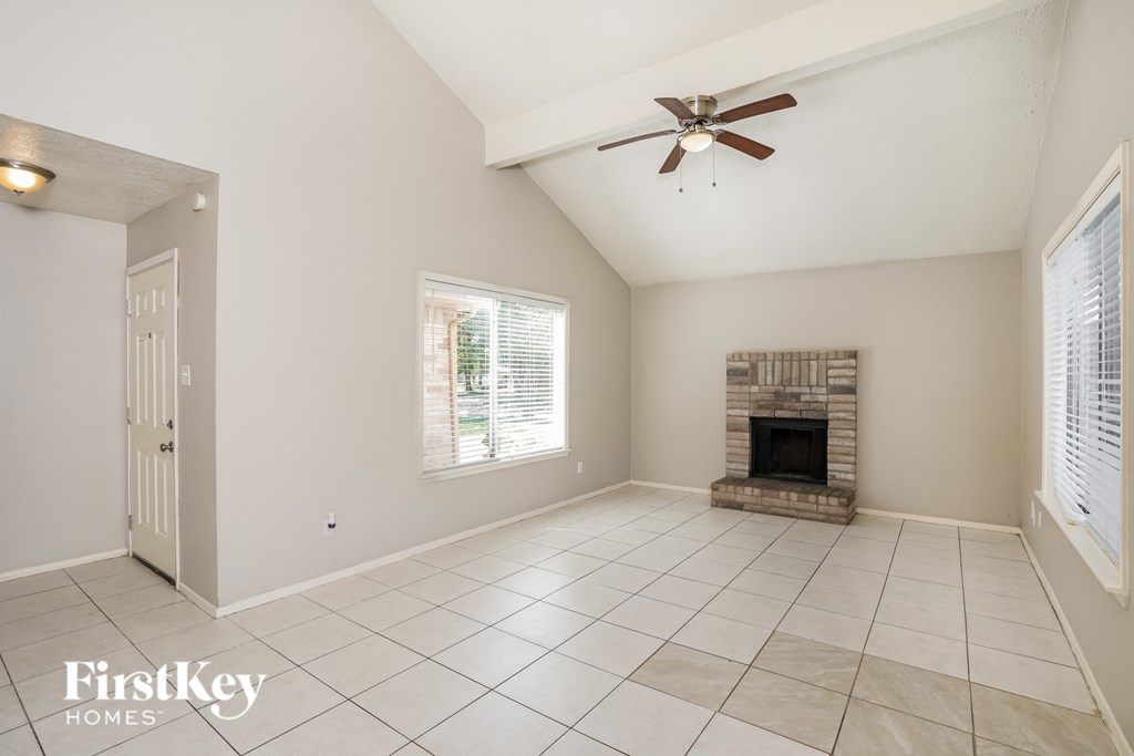 A spacious room with a fireplace and a ceiling fan.