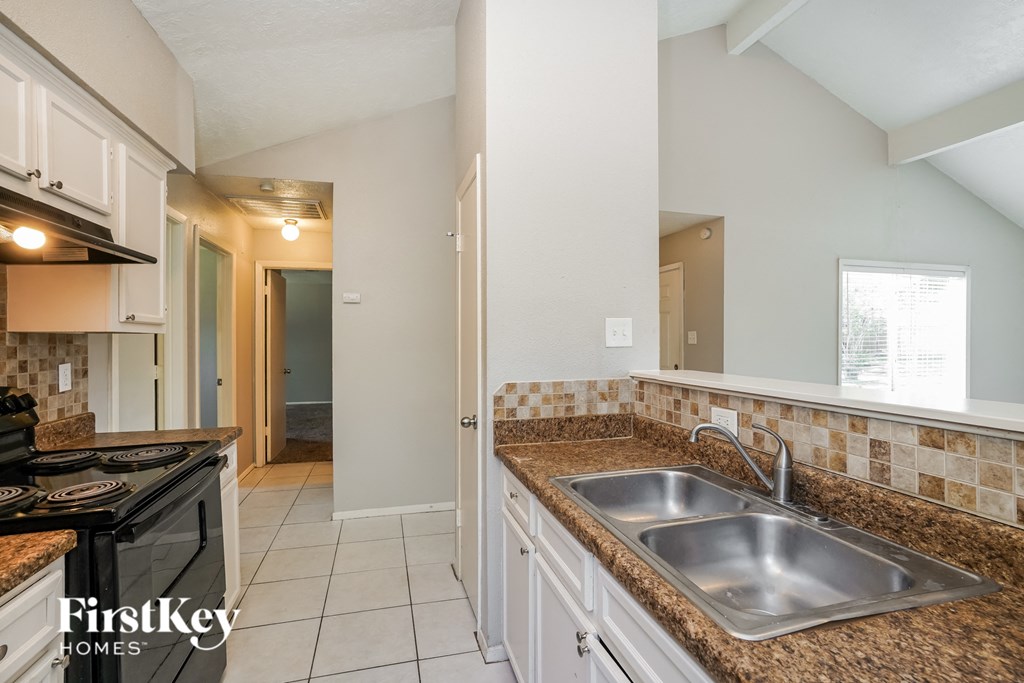 A kitchen with a stove top oven and a sink.