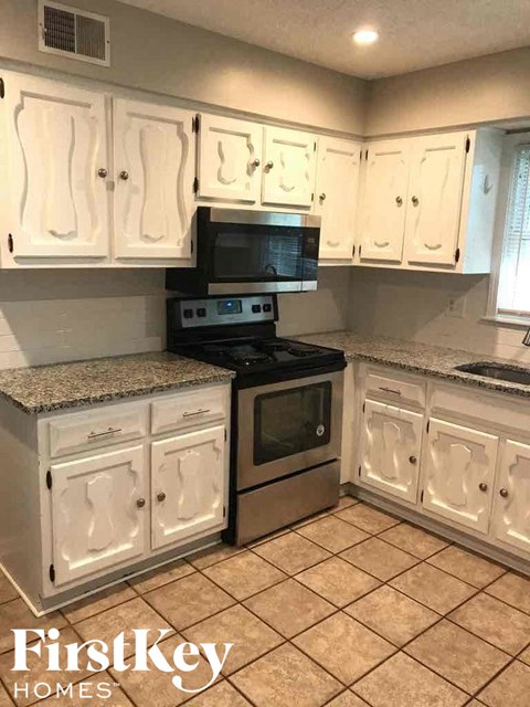 A kitchen with white cabinets and a granite countertop.