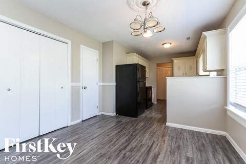 A kitchen with a black fridge and wooden floors.