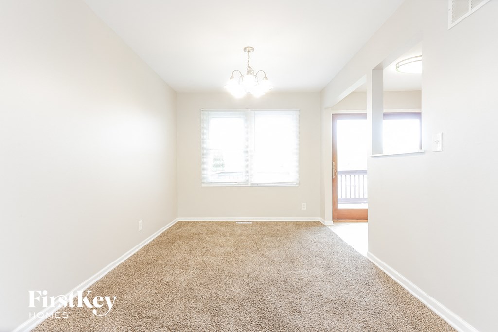 A room with a carpeted floor and a chandelier hanging from the ceiling.